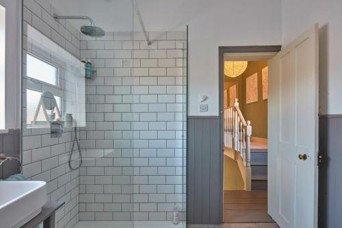 a bathroom with white subway tiles and a glass door at The Deal Abode - luxury self catering retreat in Deal