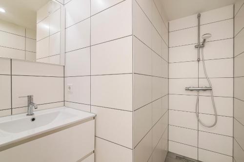 uma casa de banho branca com um chuveiro e um lavatório. em City Apartments em Leeuwarden