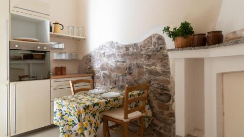 a kitchen with a table and chairs and a stone wall at Villa Il Casale Onifai in Onifai