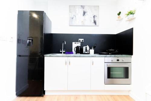 a kitchen with white cabinets and a black wall at Urban Oasis Hideaway in Birmingham
