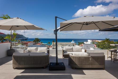 un patio con sofás, sombrillas y el océano en Coralia Hotel Cozumel, en Cozumel