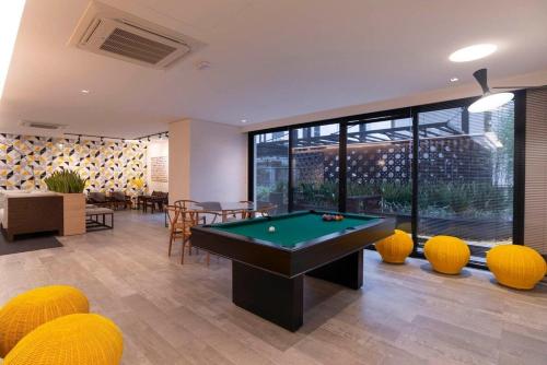 a billiard room with a pool table and yellow stools at Nun Apartments by BnbHost in São Paulo