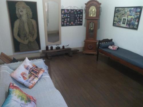 a living room with a bed and a grandfather clock at Casa Colonial. Centro Histórico in Paracatu