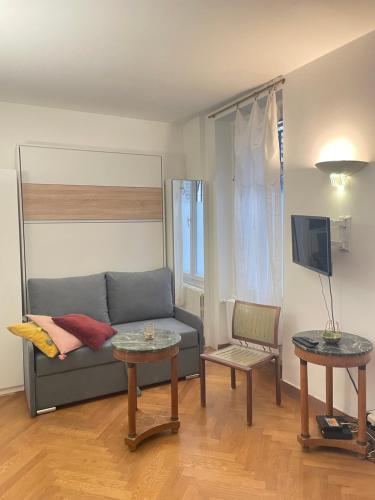 een woonkamer met een bank en 2 tafels bij Studio de Charme de Verneuil in Parijs