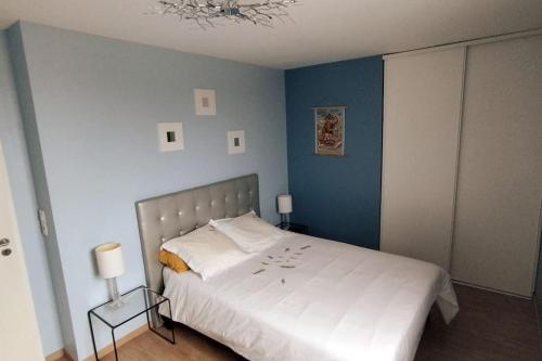 sypialnia z białym łóżkiem i niebieską ścianą w obiekcie Le Nid : Rooftop moderne surplombant la ville w mieście Nantes