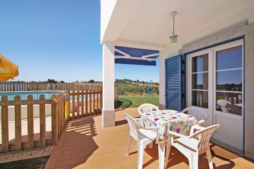 a patio with a table and chairs and a fence at Quinta da Bornacha - Casa B e Casa C in Vila Nova De Cacela