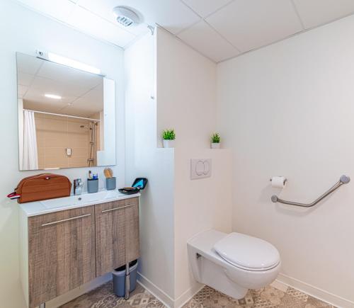 a bathroom with a toilet and a sink and a mirror at Montempô + Apparthôtel Toulouse Cité Internationale in Toulouse