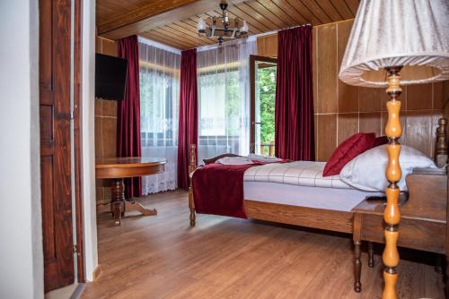 - une chambre avec un lit, une table et une lampe dans l'établissement Forest Resort, à Băile Tuşnad