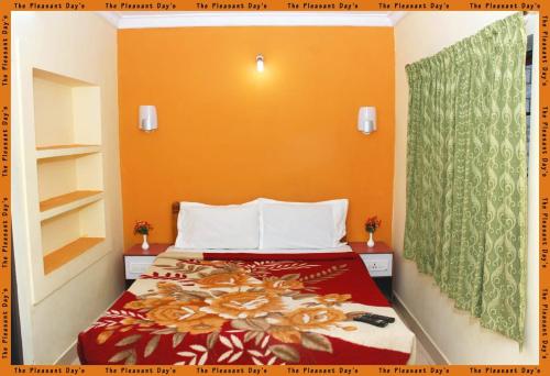 een slaapkamer met een bed met een oranje muur bij The Pleasantdays lnn in Ooty