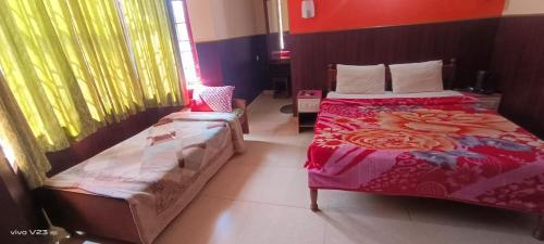 a bedroom with two beds and a chair in it at The Pleasantdays lnn in Ooty