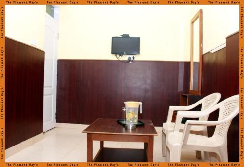 a living room with a table and chairs and a tv at The Pleasantdays lnn in Ooty