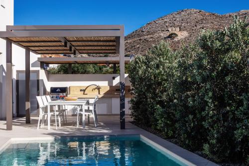 a patio with a table and chairs next to a swimming pool at Villa Venetiko - Refined Minimalist Villa with Sunset Bliss by etouri in Chania
