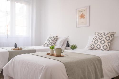 Duas camas num quarto com paredes brancas em Tetuan street apartment em Santander