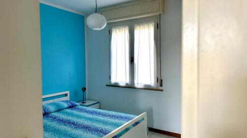 een blauwe slaapkamer met een bed en een raam bij F001 - Fano, trilocale con portico a 30mt dal mare in Marotta