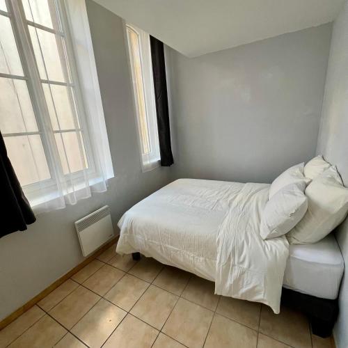 a bedroom with a white bed and two windows at Thubaneau St Charles Canebière Vieux port in Marseille