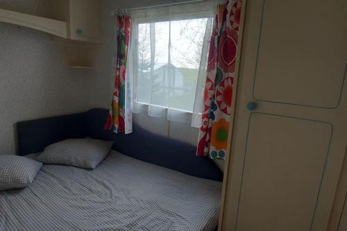 a small bedroom with a bed and a window at Domek 6-os w Campark Service " Zielony Zakątek " in Mrągowo