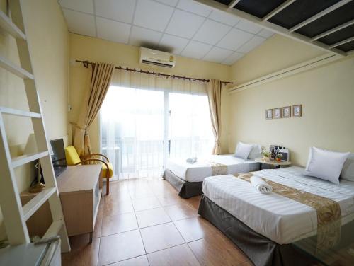 um quarto de hotel com duas camas e uma janela em EZ Sleep @ Ratchada 19 em Banguecoque