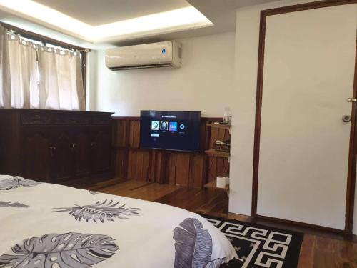 1 dormitorio con 1 cama y TV de pantalla plana en The Farm, en Puerto Princesa City