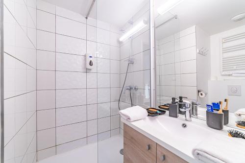 ein weißes Bad mit einem Waschbecken und einer Dusche in der Unterkunft Break & Home Paris Italie Porte de Choisy in Ivry-sur-Seine