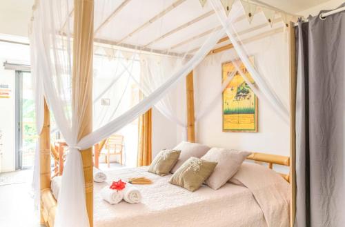 a bedroom with a white bed with a canopy at Le Ti-punch in Rivière-Pilote