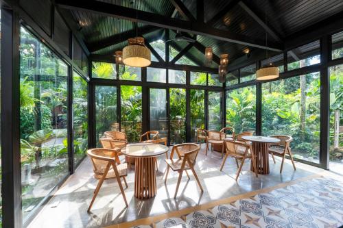 a room with tables and chairs and windows at Hideaway Rio Celeste Hotel in Bijagua