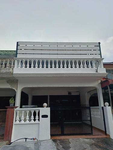 a white house with a balcony on top of it at HEAVEN HOMESTAY in Nibung Tebal