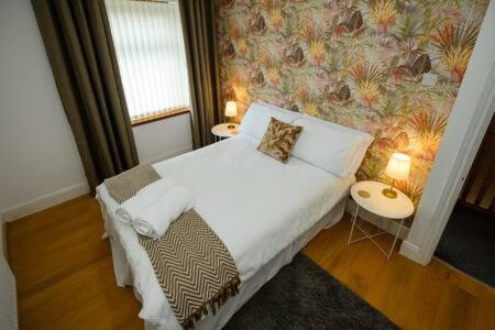 um quarto com uma cama e duas mesas com candeeiros em Heritage Cottage by StayStaycations em Pontypridd