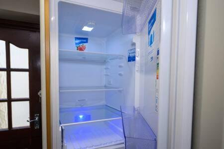 an empty refrigerator with its door open in a room at Heritage Cottage by StayStaycations in Pontypridd