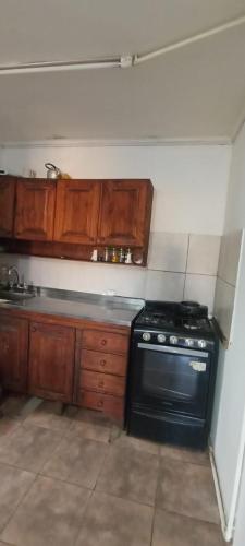 uma cozinha com um fogão preto e armários de madeira em Departamento 2 habitaciones em Concepción del Uruguay