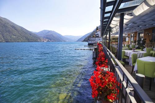 a restaurant with red flowers on the side of a lake at Villa Belvedere Como Lake Relais in Argegno