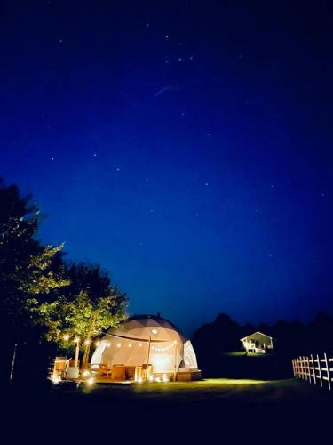 Tienda iluminada en un campo por la noche en Sandringham Safari Tent Lodge, en South Creake