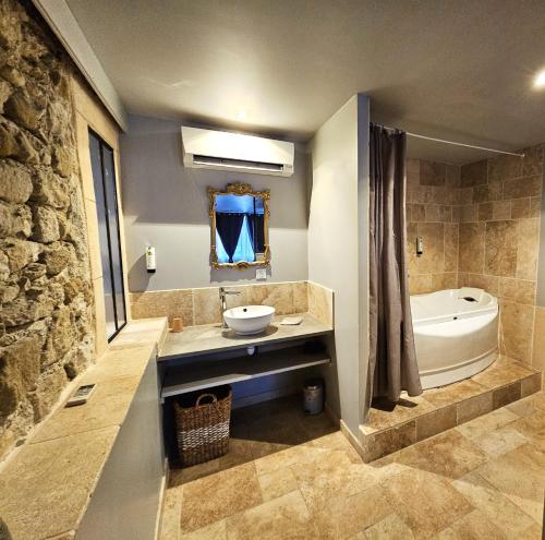 a bathroom with a sink and a bath tub and a sink at La fontaine de rocoule in Rochefort-en-Valdaine