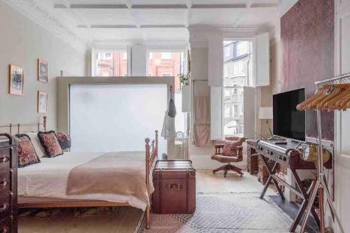 a bedroom with a bed and a desk and a television at Bright & Spacious West London Apartment in London