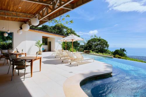 an outdoor patio with a table and chairs and a swimming pool at Vista Celestial in Uvita