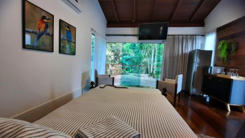 a bedroom with a bed and a tv and a window at Casa da Mata in Itapema