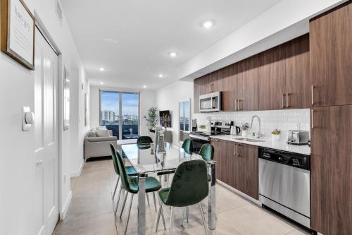 a kitchen with a glass table and green chairs at Gorgeous 3-Bed Retreat Mins from Bayside and Parking in Miami