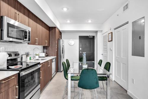 a kitchen with a glass table and green chairs at Gorgeous 3-Bed Retreat Mins from Bayside and Parking in Miami