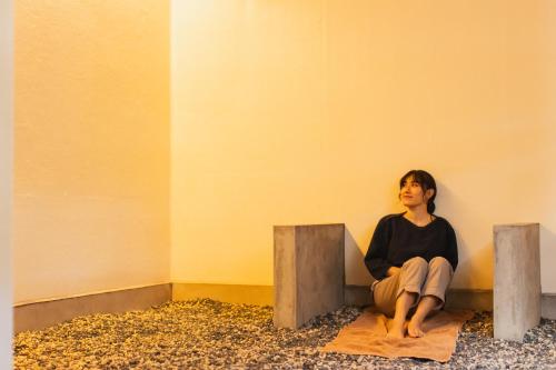 a woman sitting on a ledge in a room at Square 8 HAKUBA RETREAT by UNPLAN in Hakuba