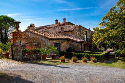 an old stone house with flowers in front of it at Agriturismo Le Roghete in Acquapendente