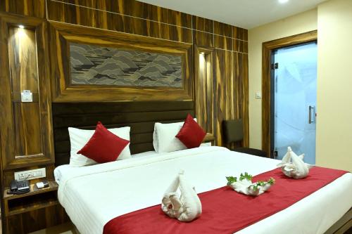 a bedroom with a large white bed with red pillows at Hotel Trax International in Jamshedpur