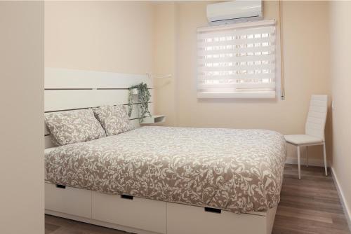 a bedroom with a bed and a window and a chair at Non Stress Nuevo Turia in Valencia
