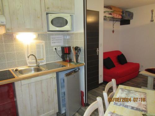 une petite cuisine avec un évier et un fauteuil rouge dans l'établissement Studio Ceriséma Pyrénées Zénith, à Luz-Saint-Sauveur