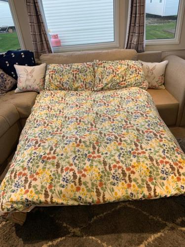 a bed with a flowered blanket on a couch at Victory Coaster in Seasalter