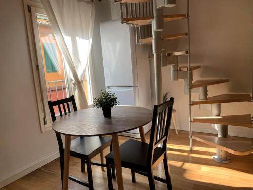 une salle à manger avec une table et des chaises ainsi qu'un escalier en colimaçon dans l'établissement Appartamento in centro - San Giovanni in Persiceto, à San Giovanni in Persiceto