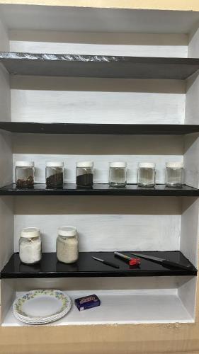 a shelf in a kitchen with jars and a plate at Kokaris Coorg Homestay in Kushālnagar