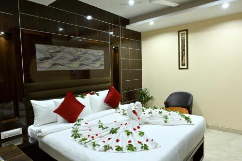 Un dormitorio con una gran cama blanca con almohadas rojas. en Hotel Trax International, en Jamshedpur