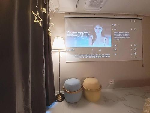 a projection screen in a room with two trash cans at Relax-편안한영화관,130인치대형스크린,넷플,디즈니플러스,넓은객실,장기숙박추천 in Namyangju