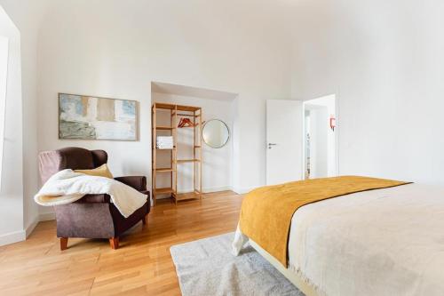 a bedroom with a bed and a chair at Home near Évora's main square with private terrace in Évora