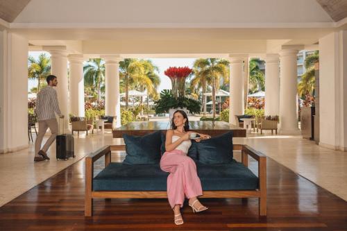 una mujer sentada en un sofá en el vestíbulo de un resort en Hyatt Zilara Rose Hall Adults Only - All Inclusive en Montego Bay
