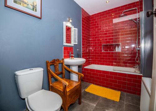 La salle de bains est pourvue de murs en briques rouges, de toilettes et d'un lavabo. dans l'établissement Marianne Cottage, à Ráistín